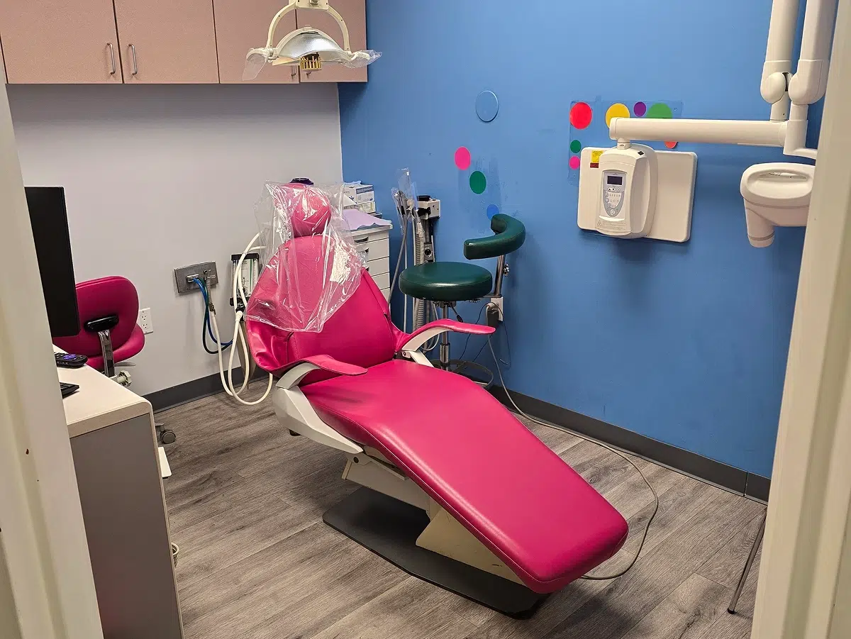 Bright pediatric dental exam room with a pink chair, blue walls, and dental equipment at Long Island Pediatric Dentistry in Lawrence, NY