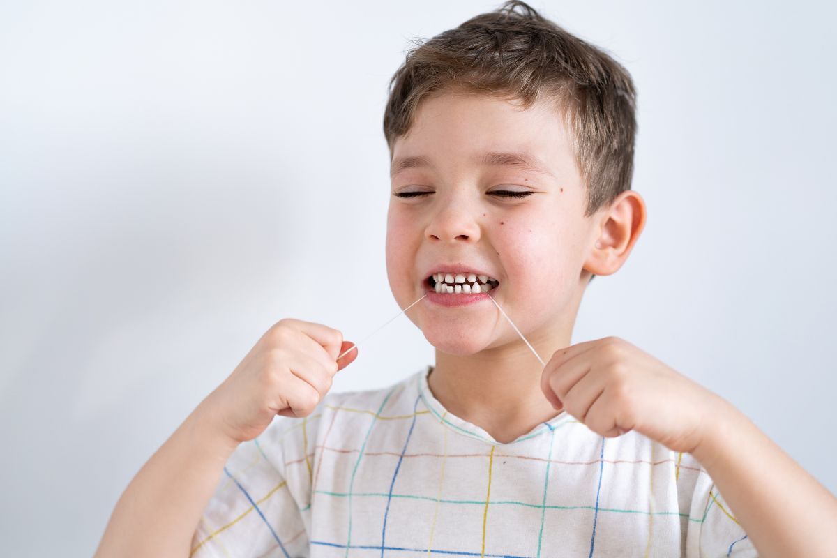 Young child flossing teeth as part of a healthy daily oral hygiene routine in Lawrence, NY