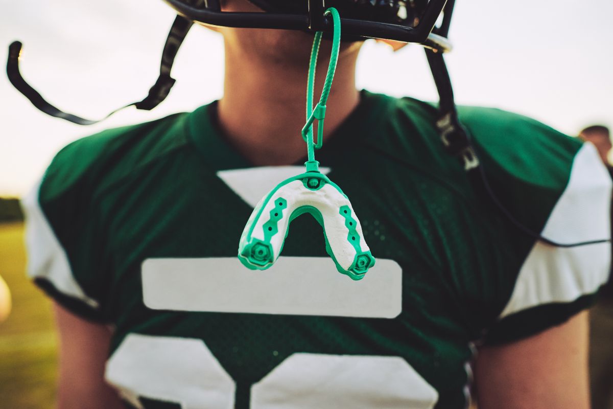 Early Warning Signs of Jaw Problems in Children shown by a young football player wearing a helmet with a protective mouthguard to help prevent jaw and dental injuries during sports.